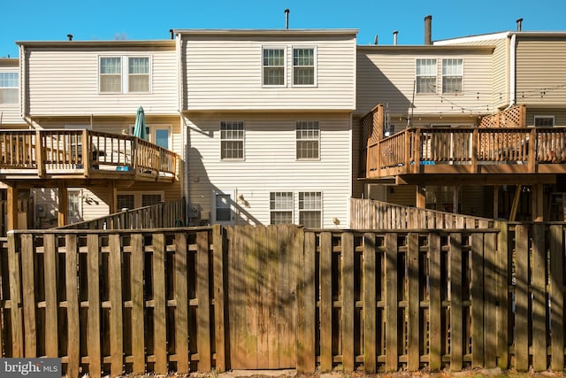 rear view of house with fence and a wooden deck