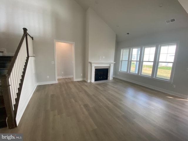 unfurnished living room with dark hardwood / wood-style flooring and high vaulted ceiling