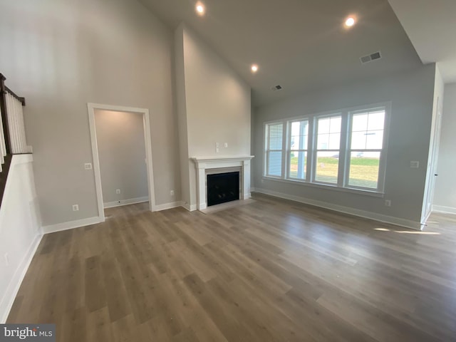 unfurnished living room featuring high vaulted ceiling and dark hardwood / wood-style floors