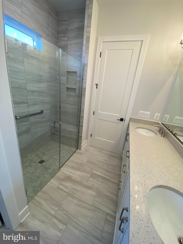 bathroom featuring a shower with door and vanity