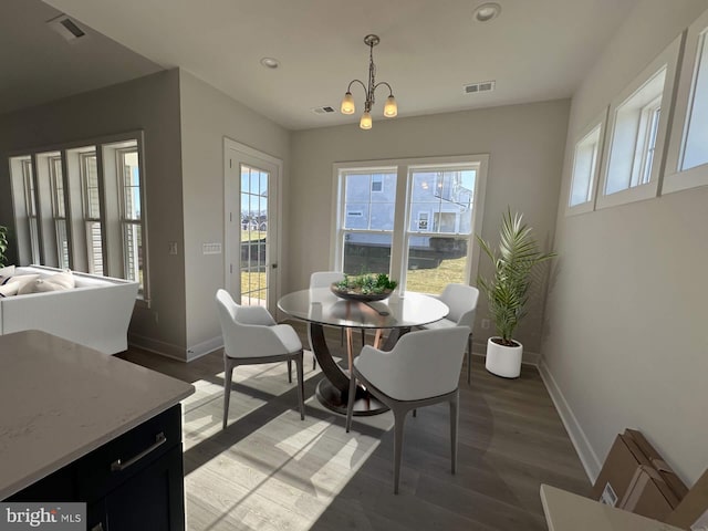 dining space with hardwood / wood-style floors, a wealth of natural light, and a chandelier