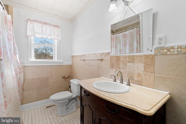 bathroom with tile walls, toilet, tile patterned floors, and vanity