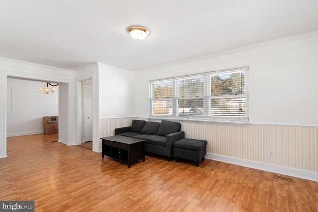 living room featuring a chandelier, ornamental molding, and light hardwood / wood-style flooring