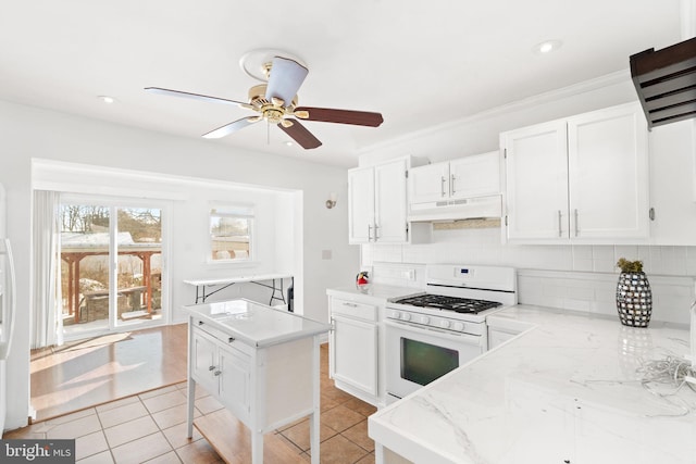 kitchen featuring white cabinetry, light tile patterned floors, tasteful backsplash, and white gas stove