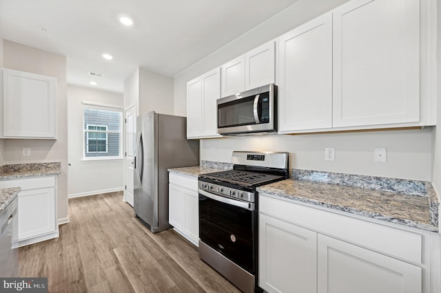 kitchen featuring appliances with stainless steel finishes, light hardwood / wood-style floors, and white cabinets