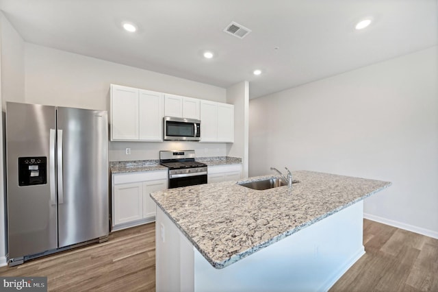 kitchen with white cabinets, appliances with stainless steel finishes, a kitchen island with sink, and sink