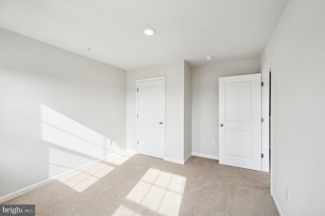 unfurnished bedroom featuring light colored carpet and a closet