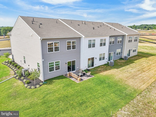 rear view of property with a lawn, central air condition unit, and a patio area