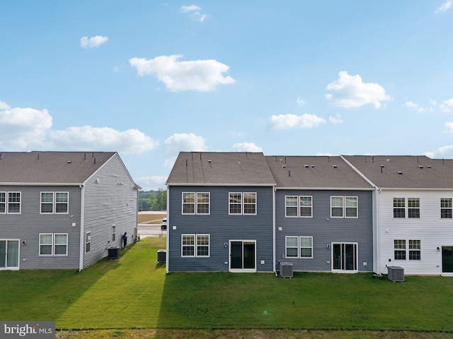 rear view of property featuring a lawn and central AC unit