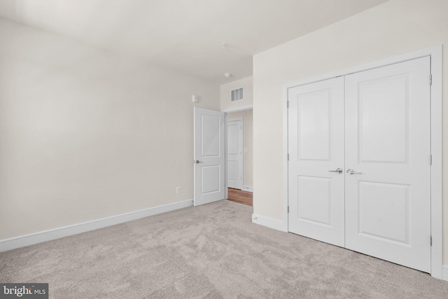 unfurnished bedroom featuring a closet and light carpet