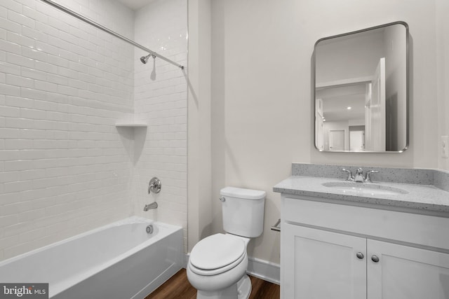 full bathroom featuring vanity, hardwood / wood-style floors, tiled shower / bath combo, and toilet