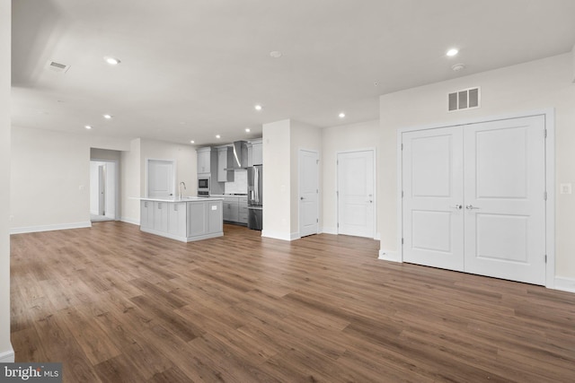 unfurnished living room featuring sink and wood-type flooring