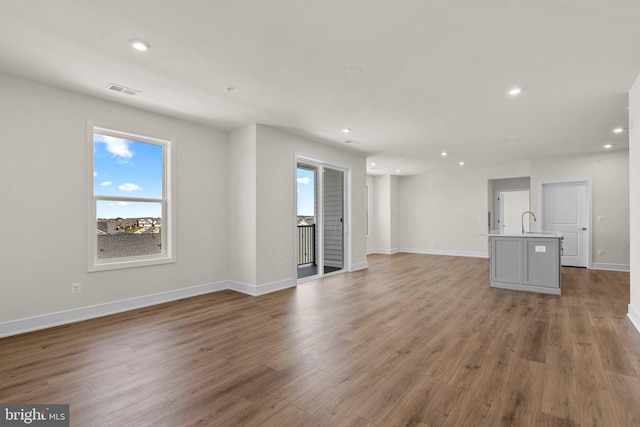 unfurnished living room with light hardwood / wood-style flooring and sink