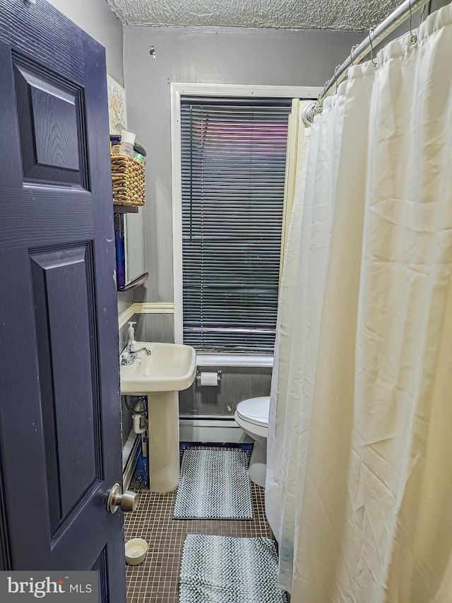 bathroom with a shower with curtain, toilet, tile patterned flooring, and a textured ceiling