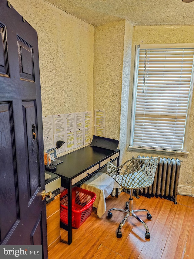 home office with radiator, hardwood / wood-style flooring, and a healthy amount of sunlight