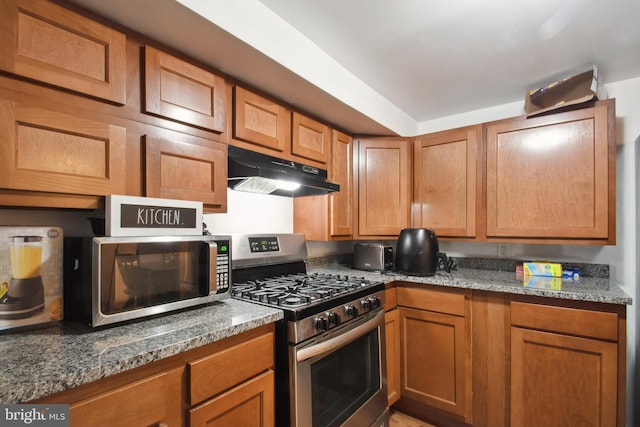 kitchen with stainless steel appliances and dark stone countertops