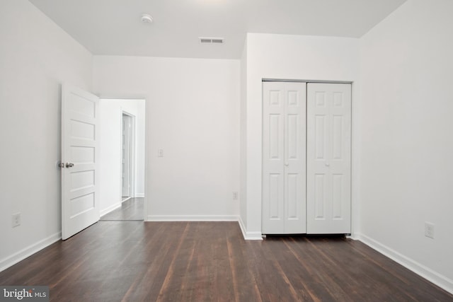 unfurnished bedroom with dark wood-type flooring and a closet