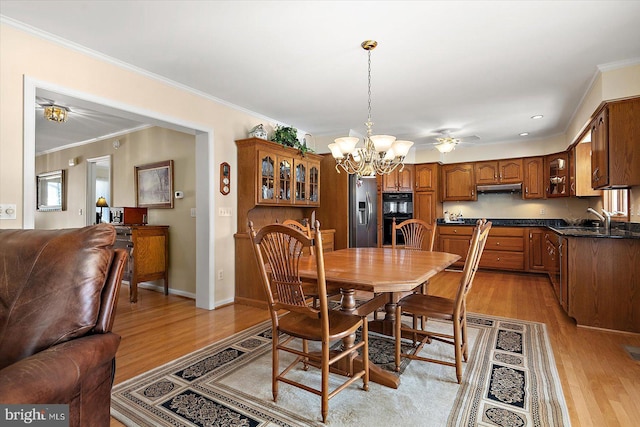 dining room featuring sink, light hardwood / wood-style flooring, and crown molding