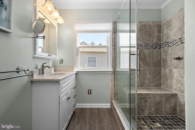 bathroom featuring a tile shower, wood-type flooring, vanity, and ornamental molding