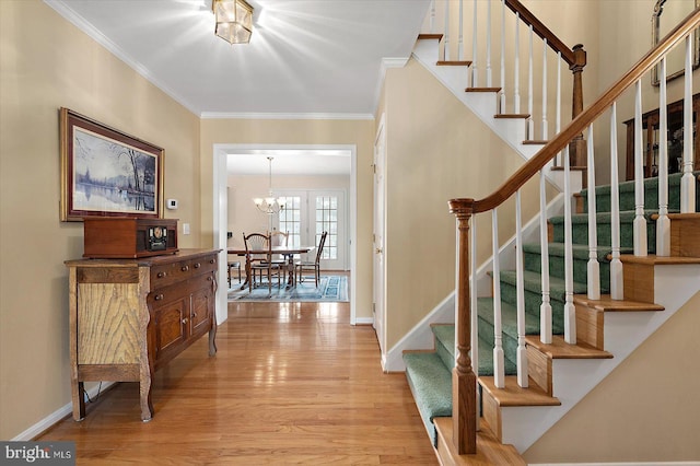 staircase featuring a notable chandelier, crown molding, and hardwood / wood-style floors