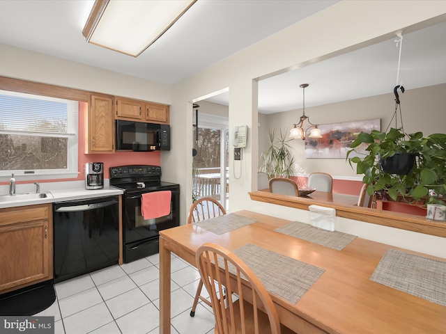 kitchen featuring black appliances, decorative light fixtures, light tile patterned floors, and sink