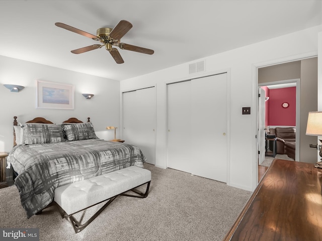 bedroom with ceiling fan, carpet flooring, and two closets