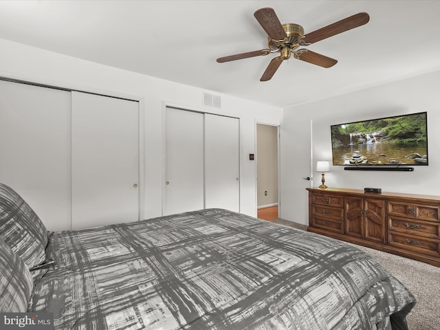 carpeted bedroom featuring ceiling fan and two closets