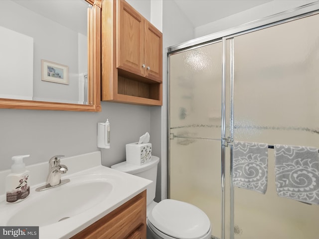 bathroom featuring vanity, toilet, and a shower with shower door