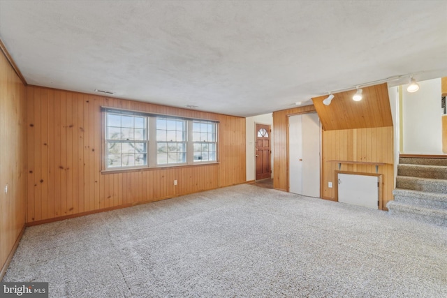 carpeted spare room with track lighting and wooden walls