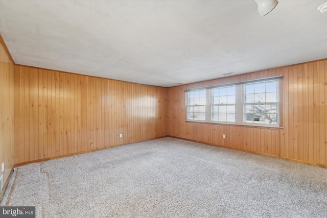 unfurnished room with wooden walls and light carpet