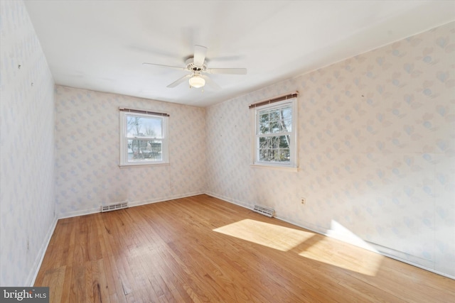 spare room featuring ceiling fan, light wood-type flooring, and plenty of natural light