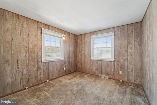 carpeted spare room with wooden walls