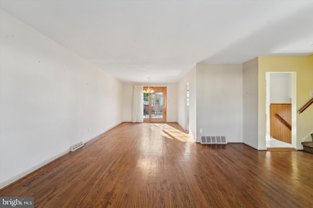 unfurnished living room featuring a chandelier and dark hardwood / wood-style floors