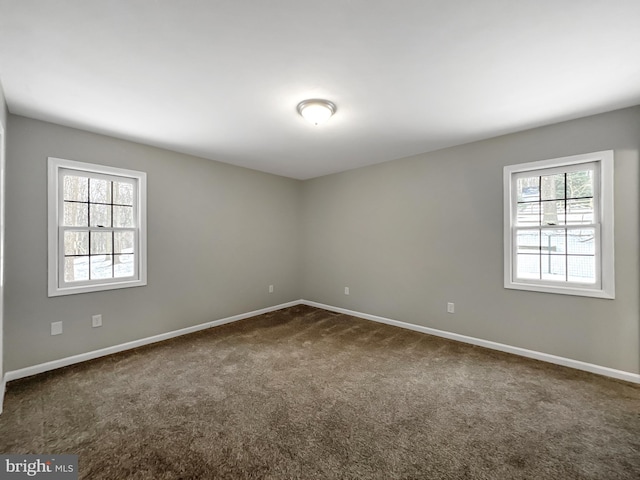 spare room with dark colored carpet