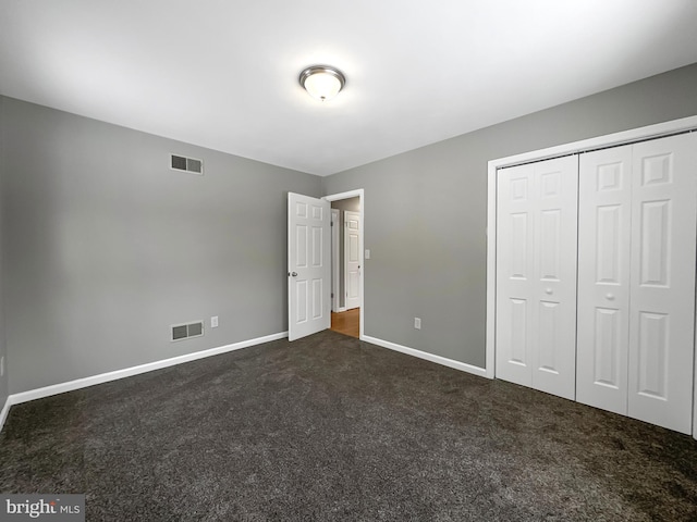 unfurnished bedroom with a closet and dark carpet