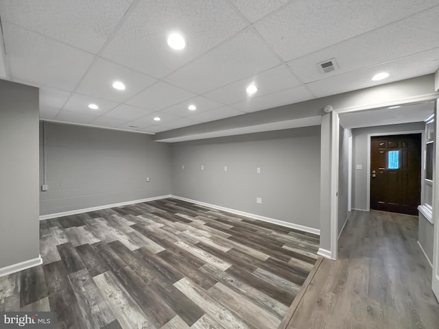 basement featuring dark wood-type flooring and a drop ceiling