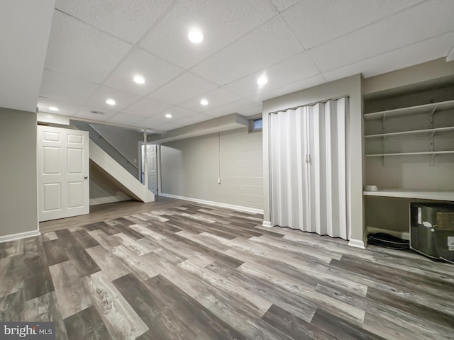 basement featuring a paneled ceiling and wood-type flooring