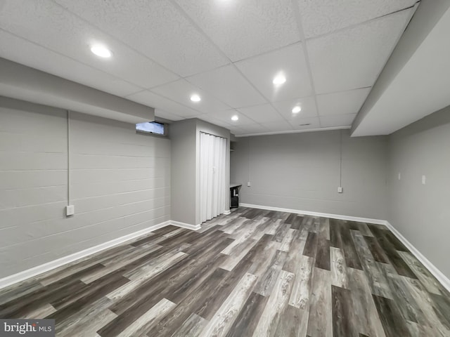 basement with a paneled ceiling and dark hardwood / wood-style floors