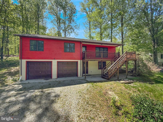 chalet / cabin with stairway, an attached garage, driveway, and a wooden deck