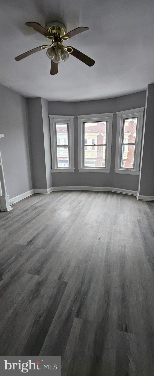 empty room featuring ceiling fan, hardwood / wood-style floors, and plenty of natural light