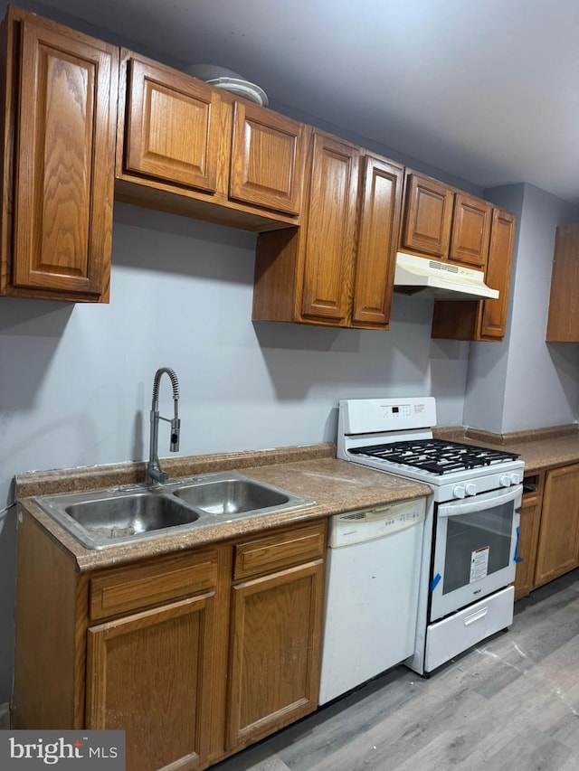 kitchen with white appliances, light wood-type flooring, and sink