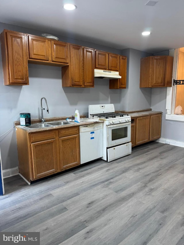 kitchen featuring white appliances, light hardwood / wood-style floors, and sink