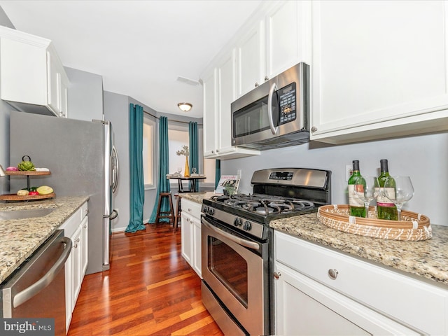 kitchen with light stone counters, dark wood-type flooring, stainless steel appliances, and white cabinets