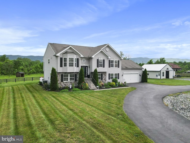 bi-level home featuring a garage, a mountain view, and a front lawn