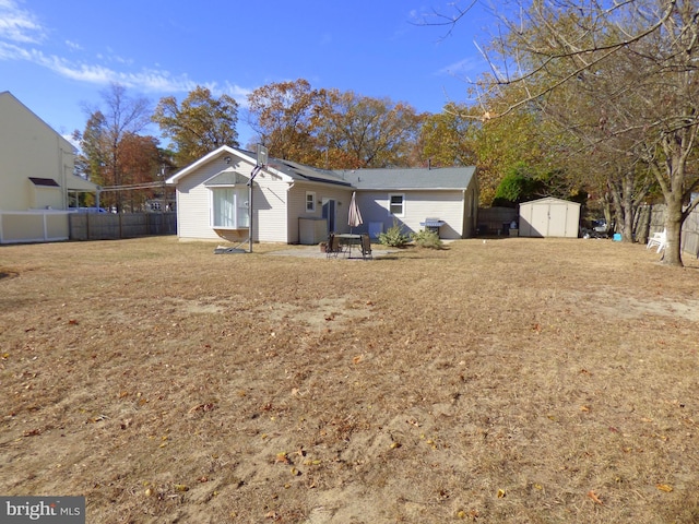 rear view of house featuring a yard, a patio area, and a storage shed