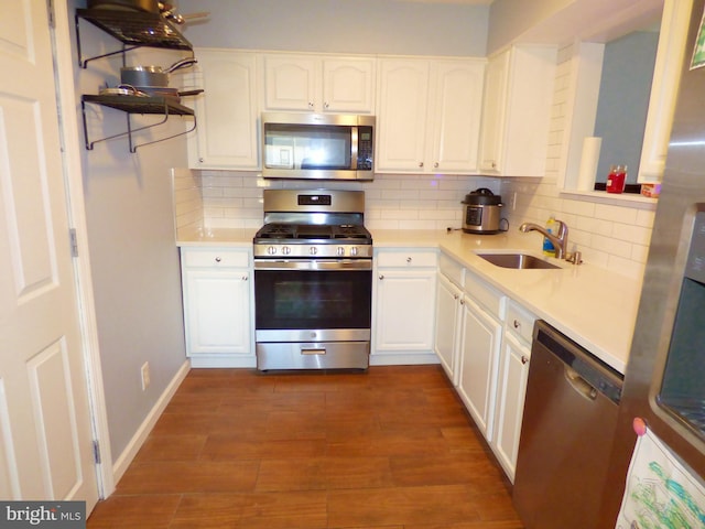 kitchen featuring appliances with stainless steel finishes, dark wood-type flooring, sink, white cabinetry, and backsplash