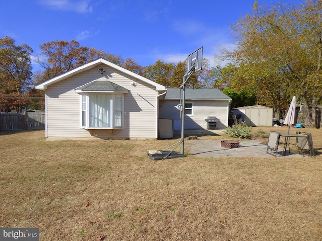 rear view of house with a patio area, a yard, a fire pit, and a storage shed