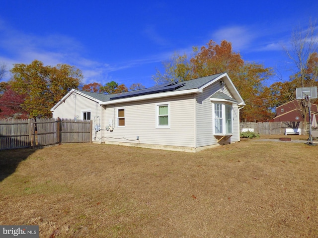 back of property with a lawn and solar panels