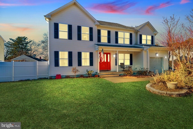 view of front of home with a lawn, covered porch, and a garage