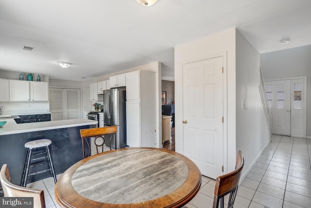 kitchen with kitchen peninsula, stainless steel appliances, a breakfast bar, white cabinetry, and light tile patterned flooring